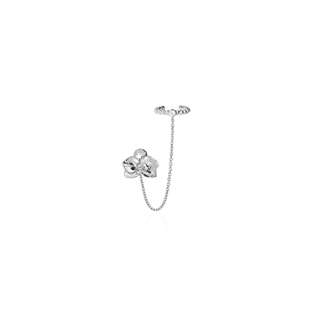 Risis Dainty Phalaenopsis Ear Cuff - A silver earring features a delicate chain linking a flower-shaped stud and a lobe-cuff, showcasing a polished, minimalist floral design.