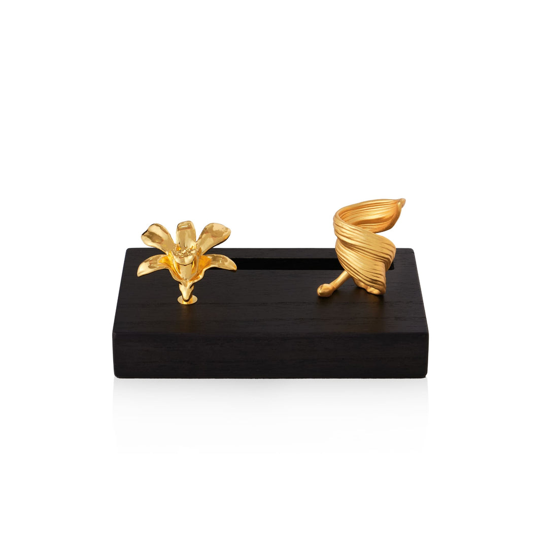 Risis Dendrobium Li Min Eng Orchid Pen And Name Card Holder - Two golden sculptures, a blooming flower and a twisted leaf, rest on a sleek, dark rectangular stand, depicting organic elegance and artistic craftsmanship.