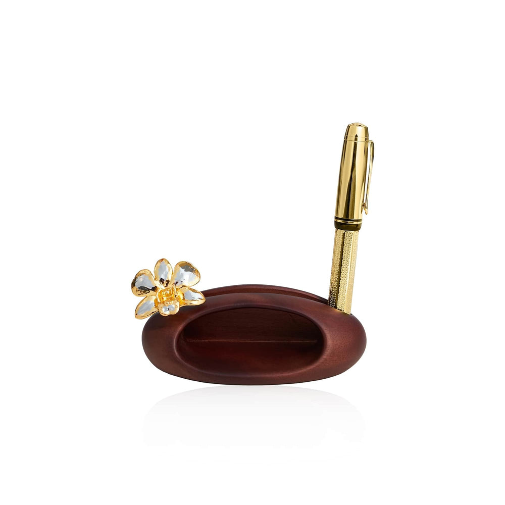 Risis Dendrobium Orchid Phone Amplifier And Pen Holder - A golden pen with a textured grip and shiny finish stands upright in a sleek, mahogany-brown oval base, accented by a gold and crystal flower adornment.
