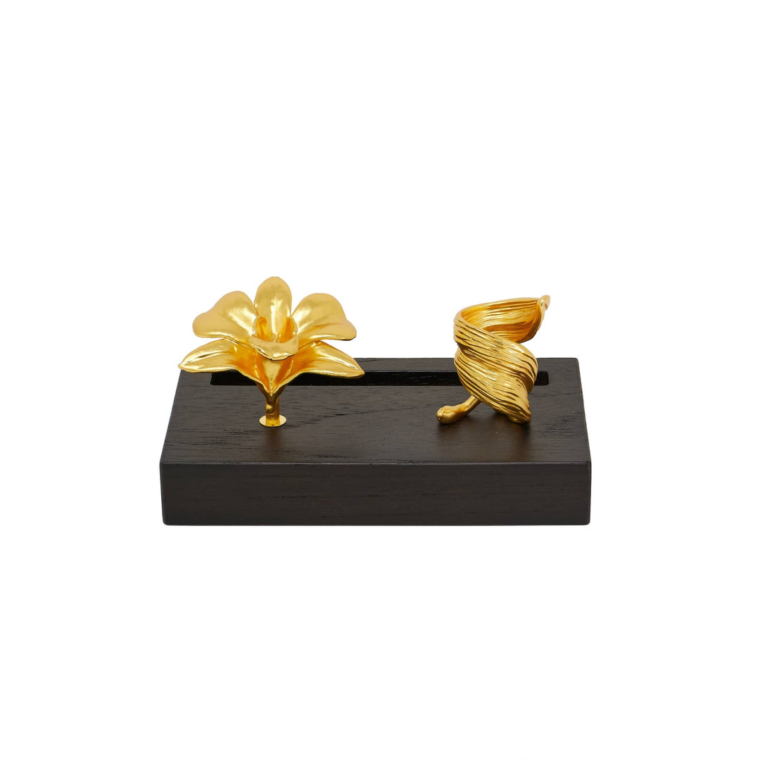Risis Dendrobium Tay Swee Keng Orchid Pen and Name Card Holder - A golden flower and twisted leaf sculpture on a dark wooden base, showcasing shiny textures and elegant lines, suggesting movement and natural beauty.