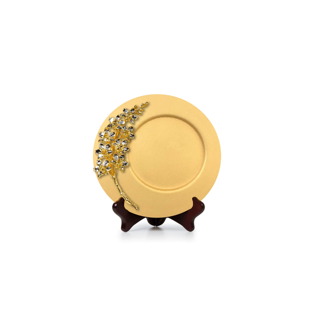 Risis Natural Doritaenopsis Purple Gem Orchid Spray On 8 Inch Plaque - A circular gold-colored plate adorned with a sparkly branch-like design embedded with clear and sapphire-blue gemstones rests on a small wooden stand.