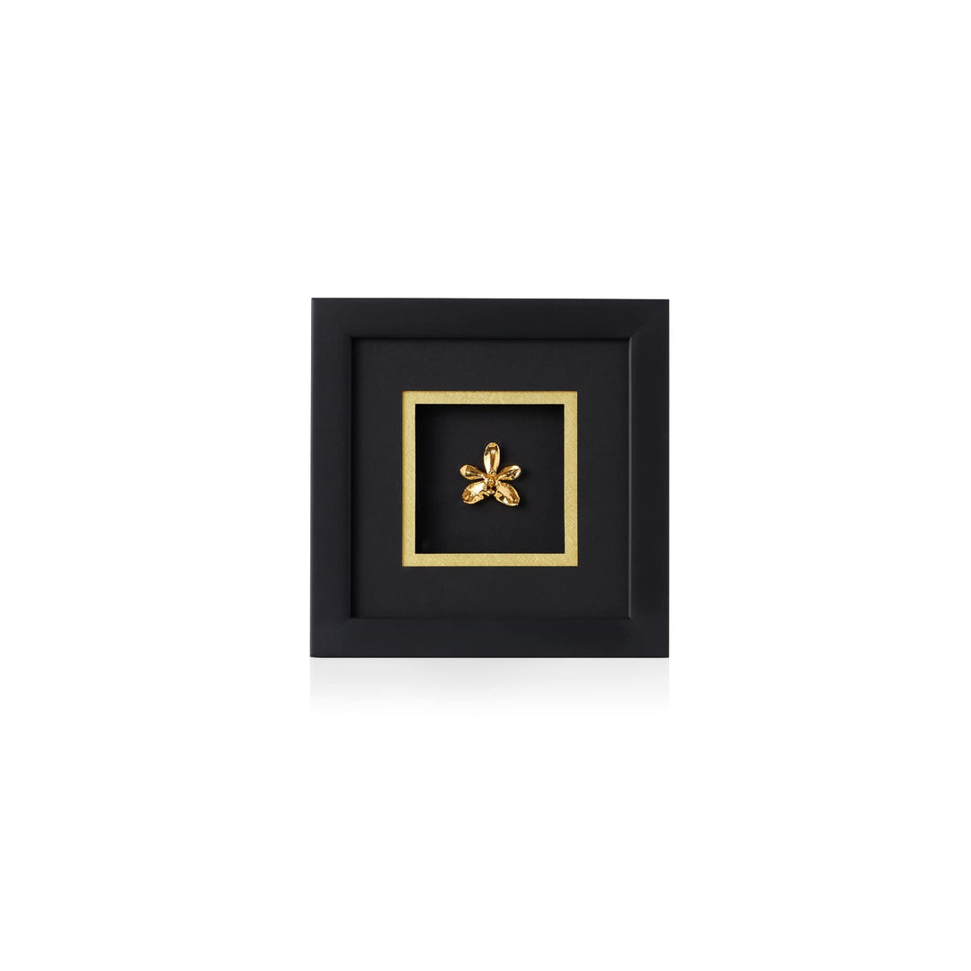 Risis Doritaenopsis Summer Red Orchid Frame - A gold-colored brooch with petal-like elements, centered within a black square frame, accented by a gold border, suggesting elegance and simplicity.