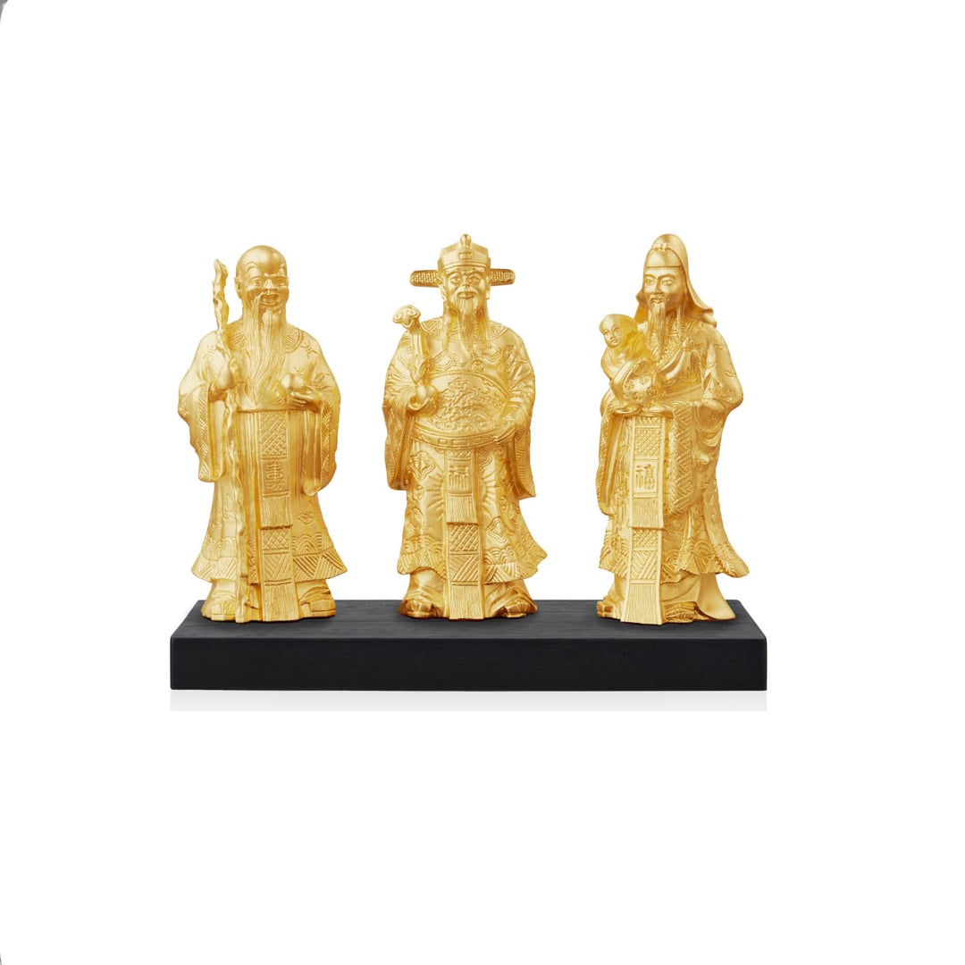 Risis Fu Lu Shou - Three intricate golden figurines, depicting venerable men in traditional robes, stand side by side on a dark base. They are adorned with detailed decorations and textures.