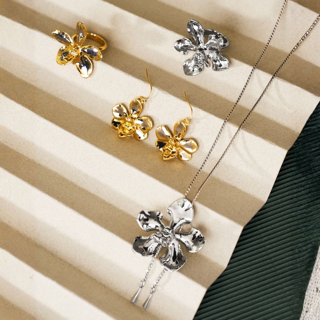 Gold and silver flower rings, flower drop earrings and a silver flower pendant necklace on cream fabric - RISIS birthday gifts