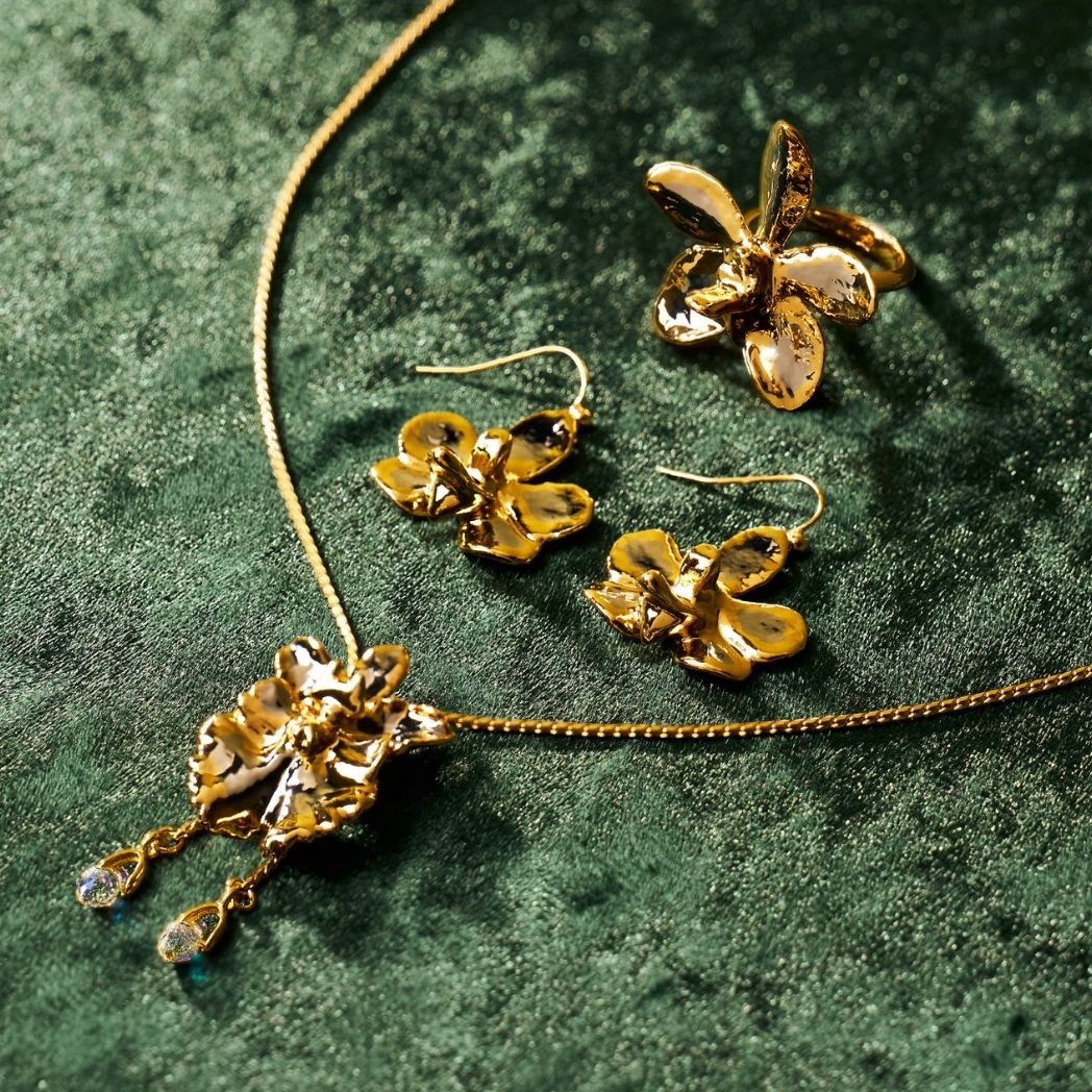 Gold orchid pendant necklace, orchid drop earrings and orchid ring on green velvet - RISIS Christmas gifts