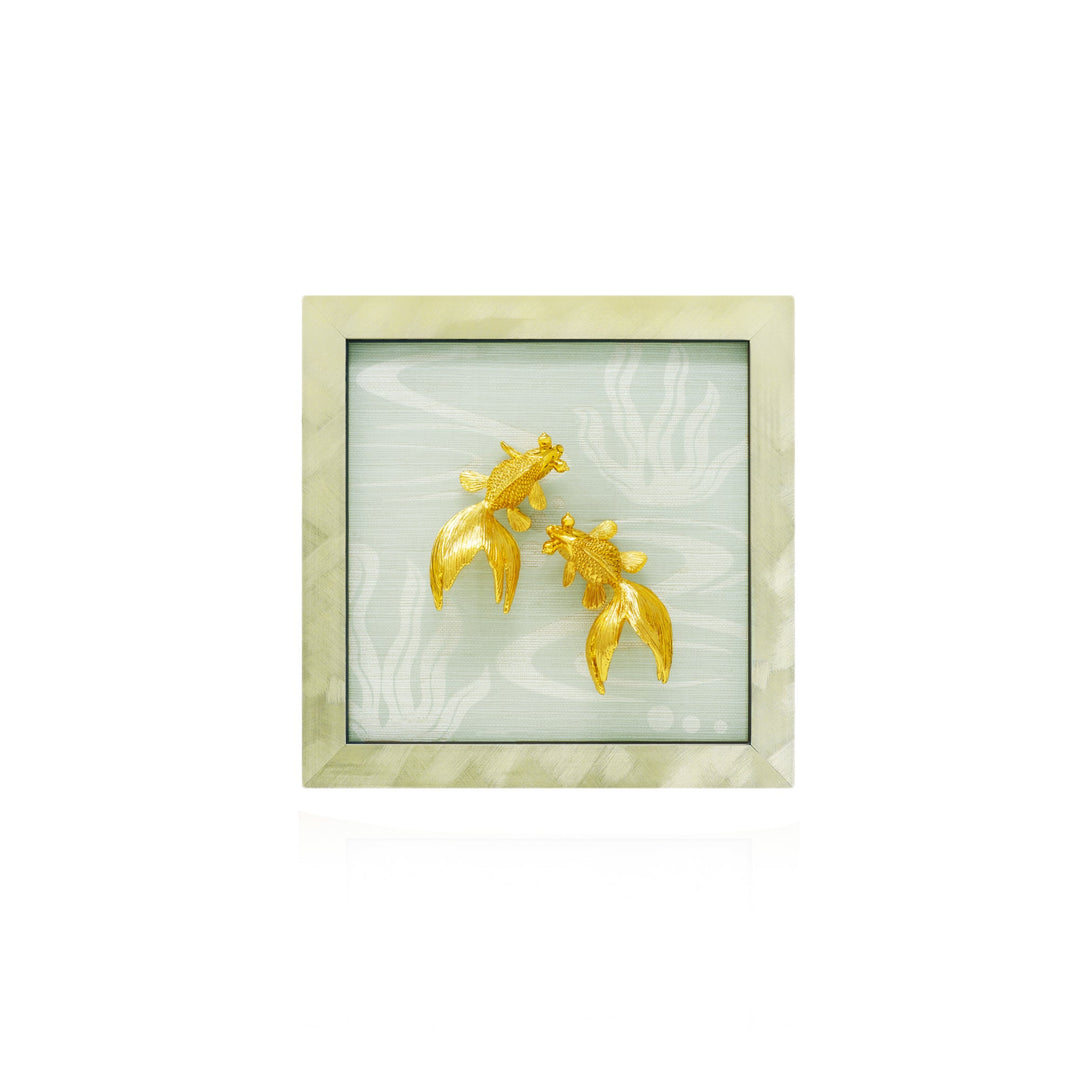 Risis Goldfish Frame IV - Golden fish-shaped jewelry, intricately textured with delicate scales and fins, displayed against a pale, patterned backdrop.