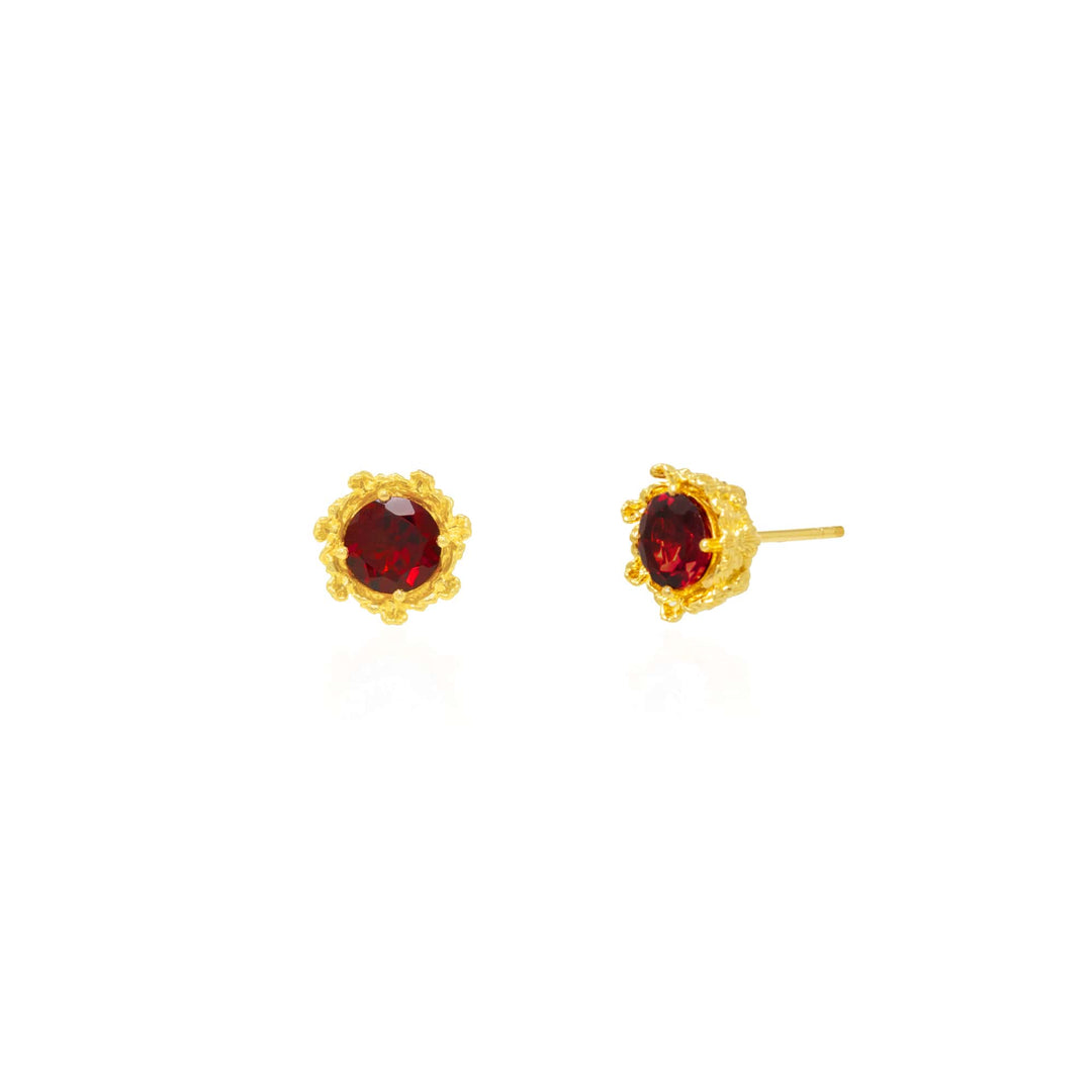 Risis Majestic Vanda Earrings With Red Garnet - A pair of gold stud earrings, each featuring a central dark red gemstone encased in a textured, ornate setting, exudes elegance and luxury.