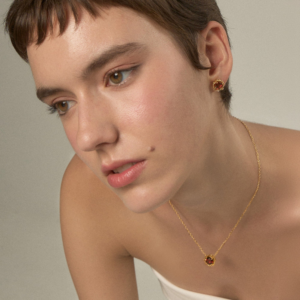 Risis Majestic Vanda Earrings With Red Garnet - A person is wearing gold earrings and a matching necklace with red gemstone pendants, exuding a simple, elegant style.