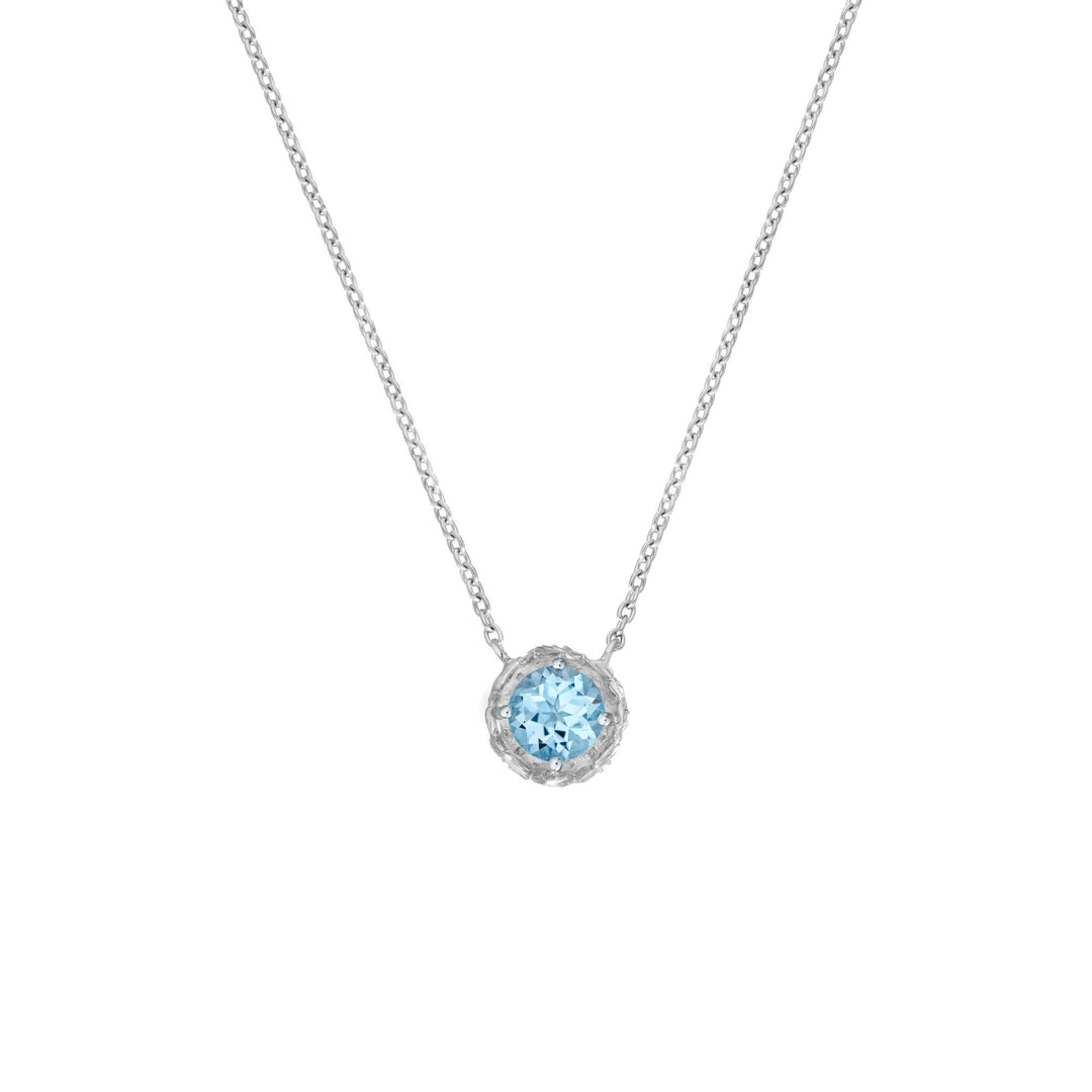 Risis Midori Necklace With Sky Blue Topaz (RH) - A silver necklace with a delicate chain holds a light blue gemstone pendant, encased in an intricate, sparkling setting.