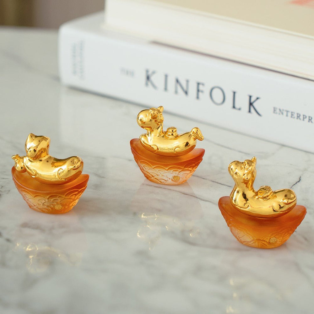 Risis Mini Celestial – Dog on Amber Liu Li - Three small, gold-and-orange figurines with ornate details and a glossy finish, displayed on a flat surface.