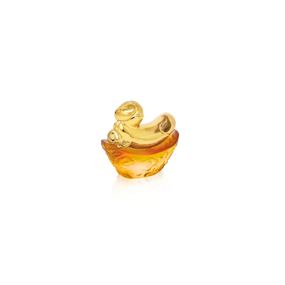 Risis Mini Celestial – Monkey on Amber Liu Li - A golden and amber-hued decorative object resembling an ornate boat with a curled front, possibly crafted from polished metal and glass, reflecting a sense of luxury and artistry.