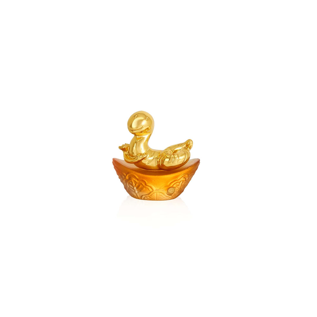 Risis Mini Celestial – Snake on Amber Liu Li - A golden figurine with a rounded, smooth body and head sits within an ornate half-shell with intricate carvings, presenting a lustrous and decorative appearance.