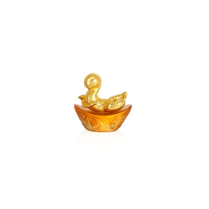 Risis Mini Celestial – Snake on Amber Liu Li - A golden figurine with a rounded, smooth body and head sits within an ornate half-shell with intricate carvings, presenting a lustrous and decorative appearance.