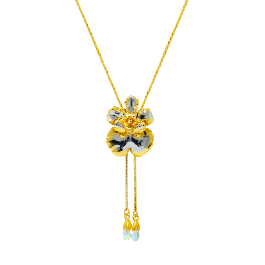Risis Oncidium Coco Drop Slider Necklace With Crystal Tailends Pg - A golden pendant necklace with a flower design featuring black and white petals, a shiny yellow center, and delicate droplets hanging from fine chains.