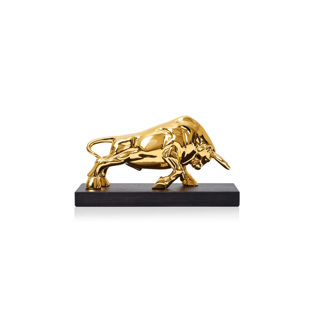 Risis Raging Bull - A glossy, golden bull sculpture poised aggressively, with detailed muscular contours, mounted on a sleek dark base.