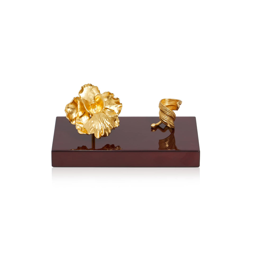 Risis Vanda Miss Joaquim Orchid and Leaf Pen Holder - A golden sculpted flower and a spiral object rest elegantly on a glossy, mahogany base, exuding luxury and artistic craftsmanship.