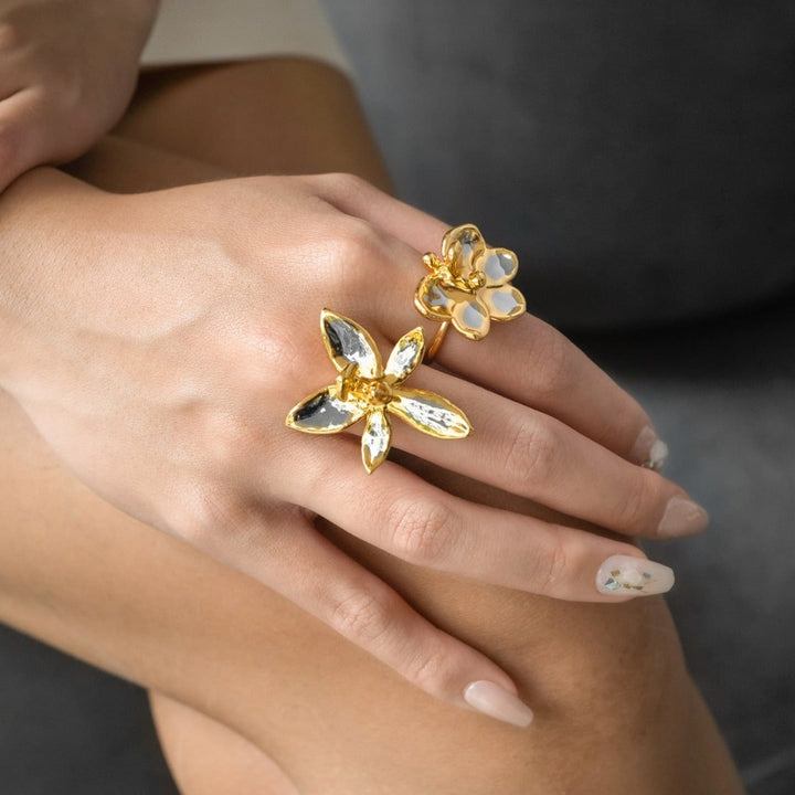 Risis Ascocenda Blossom Ring - A hand adorned with a golden floral ring featuring petals in contrasting black and white highlights, paired with elegant, neutral-toned nail polish.