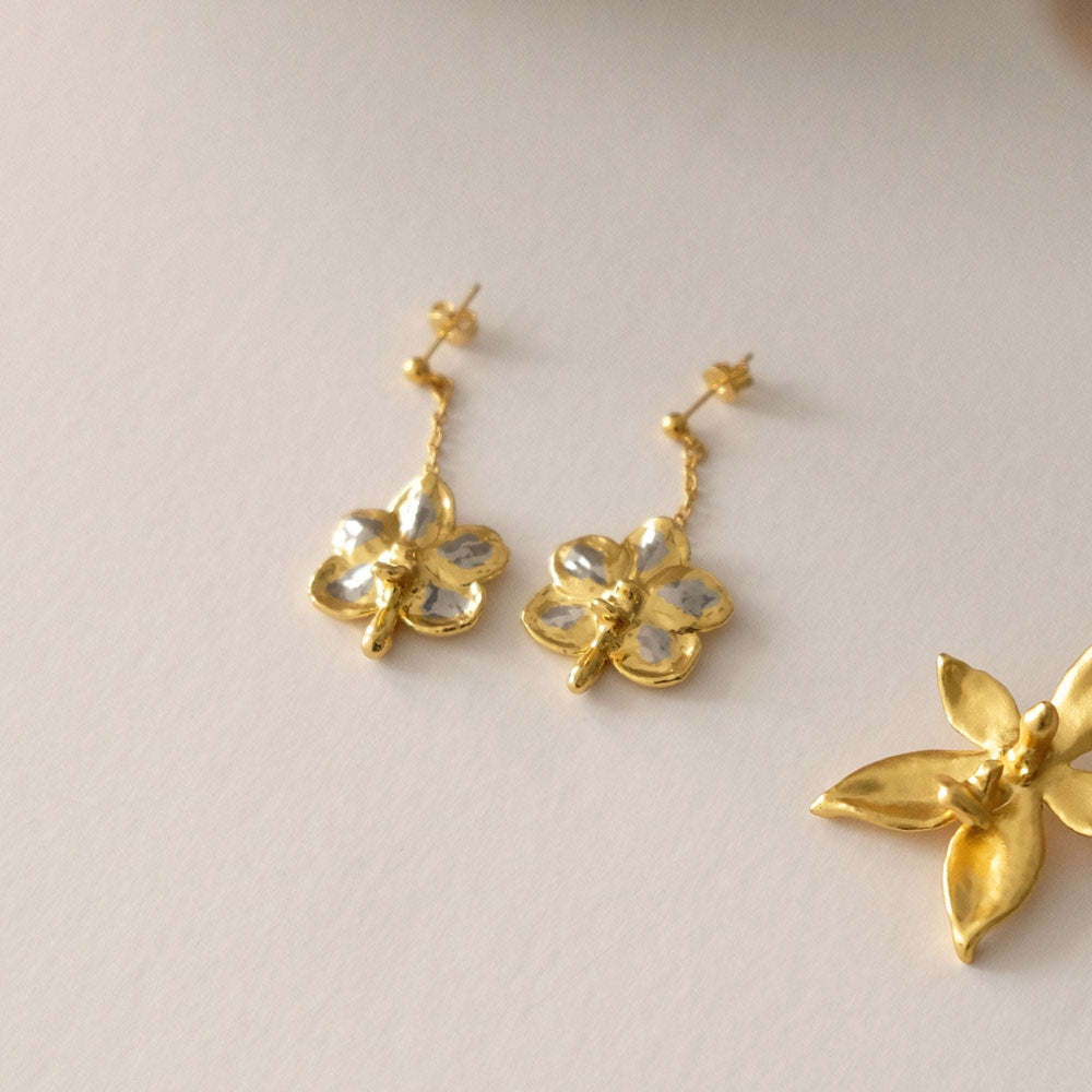 Risis Ascocenda Sagarik Gold Orchid Dangling Earrings (PG) - Golden orchid-shaped earrings with transparent gemstones at their centers, dangling elegantly, exhibiting a subtle shimmer and exquisite craftmanship.
