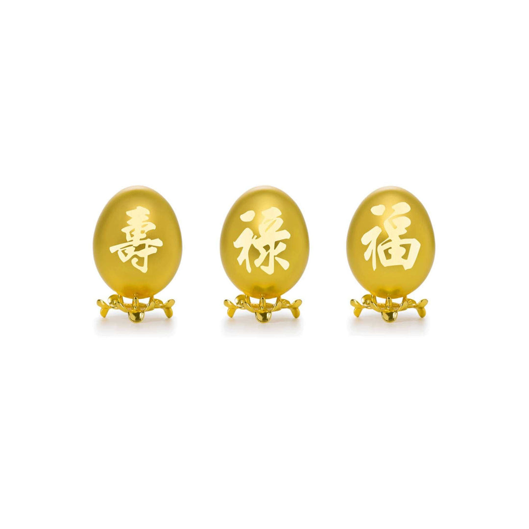 Risis Auspicious Fu Lu Shou Egg Set (Small) - Three golden-yellow oval objects with Chinese characters, mounted on intricate metallic stands, suggestive of opulence and tradition.
