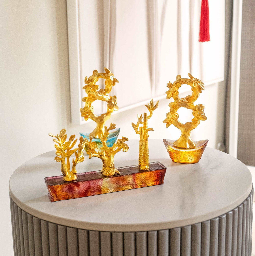 Risis Auspicious Money Tree with Bronze Liu Li Base - Three ornate golden jewelry holders with floral patterns and small blue accents stand on a marbled surface, displaying their intricate craftsmanship and elegance.