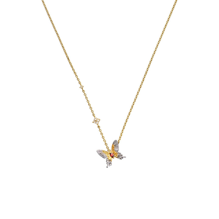 Risis Botanique Butterfly Necklace - A golden dragon sculpture rests on a wavy blue stand, with intricate detailing. Nearby, a metallic tree blooms from a small pot, and a ornate gold-splattered dish with a spoon completes the set.