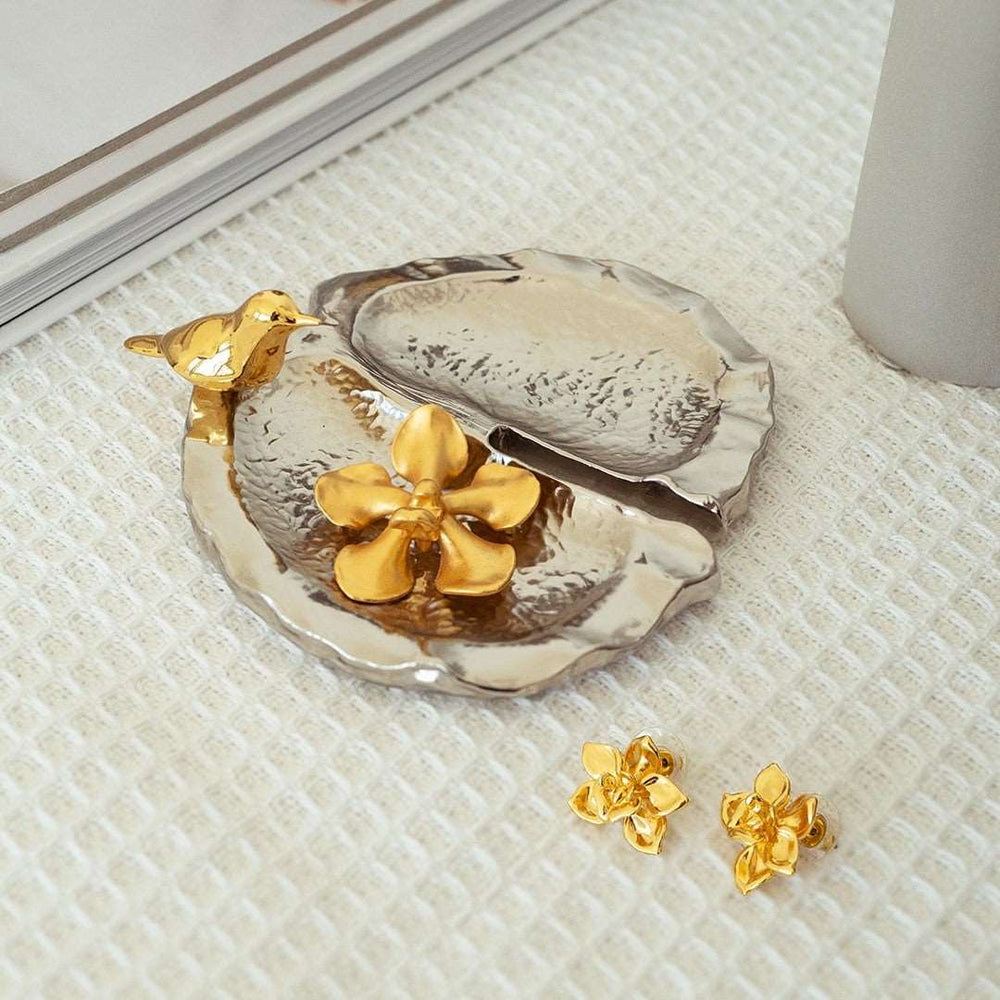 Risis Botanique Chestnut Bird Tray - A shiny, metallic clamshell-shaped object with a glossy silver surface and a contrasting gold hinge, reflecting light and highlighting its smooth, curved texture.