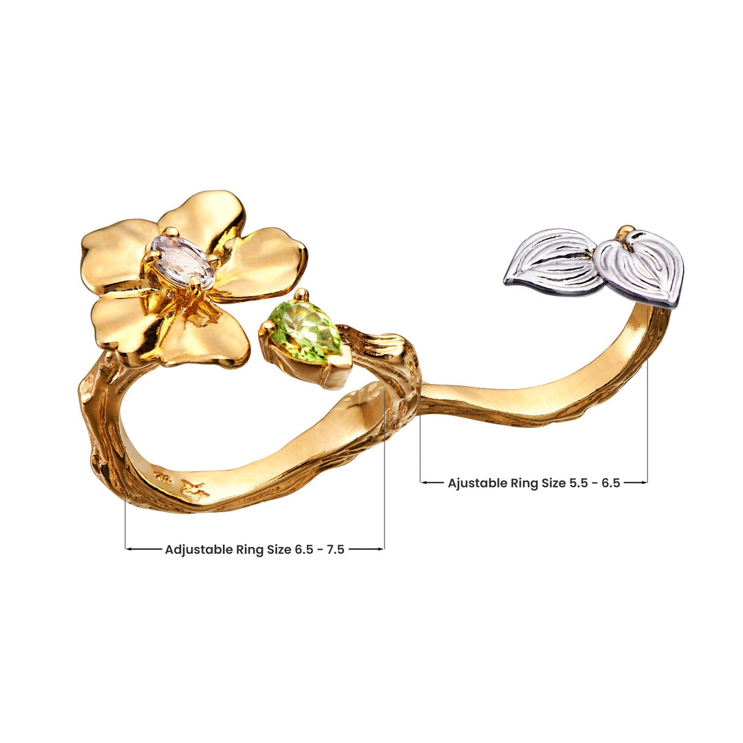 Risis Botanique Orchid Ring - A golden ring with an adjustable band, featuring a prominent flower design with a clear gem center and a green gem leaf, complemented by a smaller silver leaf detail.