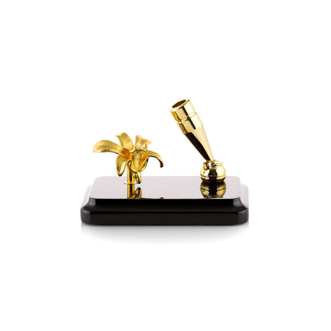 Risis Dendrobium Li Min Eng Orchid Pen Holder - A gold-colored pen and an ornate flower sculpture are displayed on a sleek black stand, embodying elegance and luxury in their polished finishes and delicate designs.