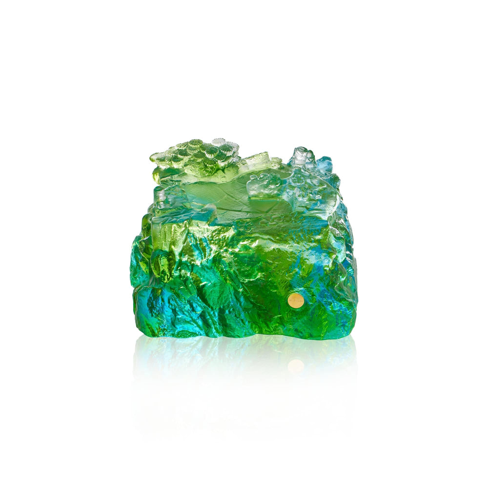 Risis Double Crane on Liu Li - A translucent, textured object with vibrant green and blue hues resembling rough, uncut gemstone with light reflecting off its irregular surface.