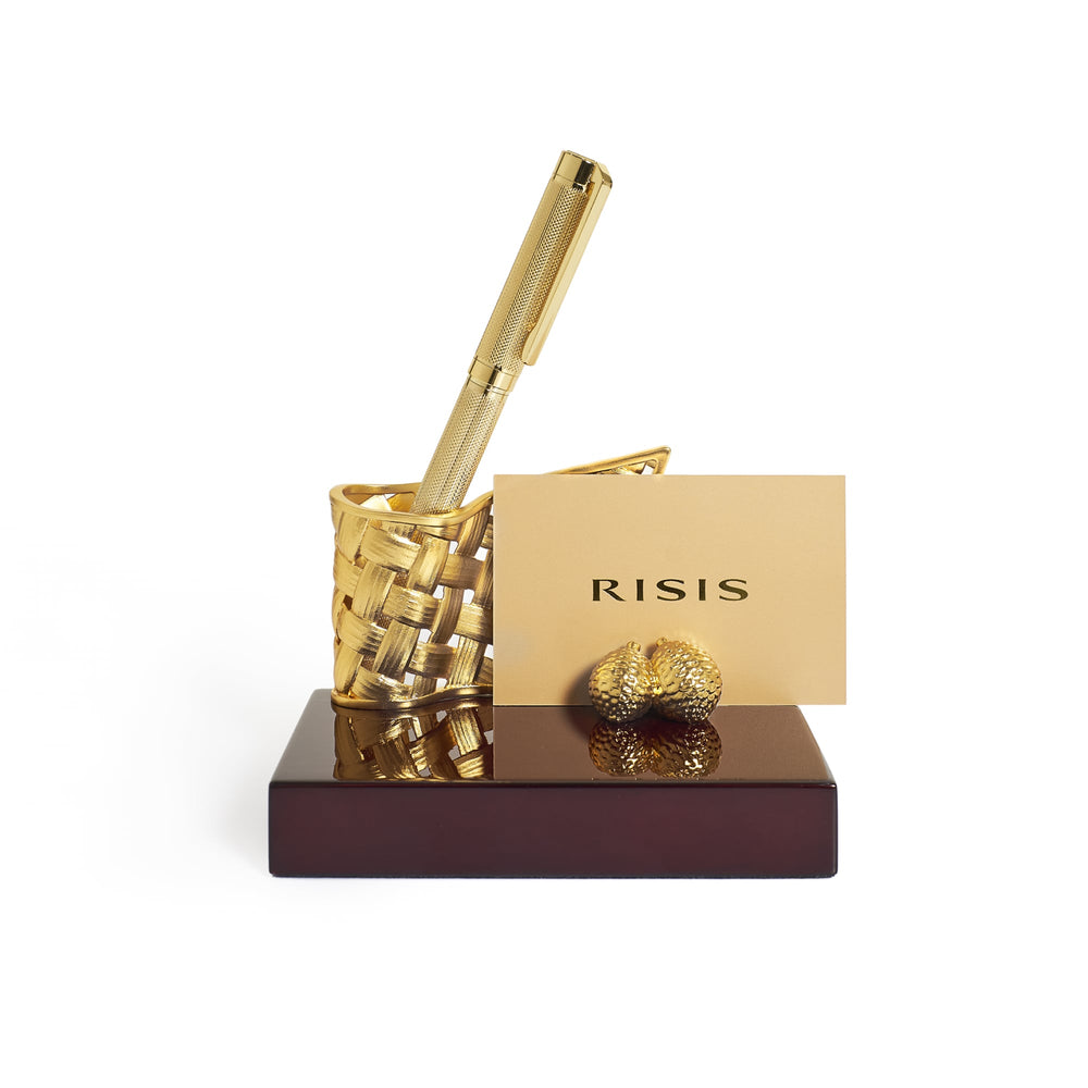 Risis Entwined Rattan Pen and Name Card Holder - A golden pen and intricately textured pen holder rest on a polished wooden base, beside a card with "RISIS" printed and a small ornate golden sculpture.