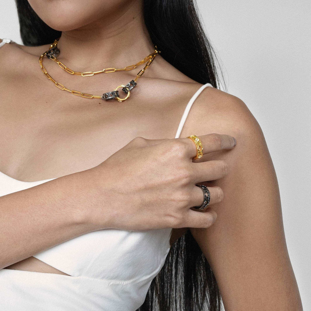 Risis Entwined Rattan Ring (BRH) - A delicate gold chain necklace featuring two interlinked circles, one embellished with tiny crystals and the other in a contrasting black tone.