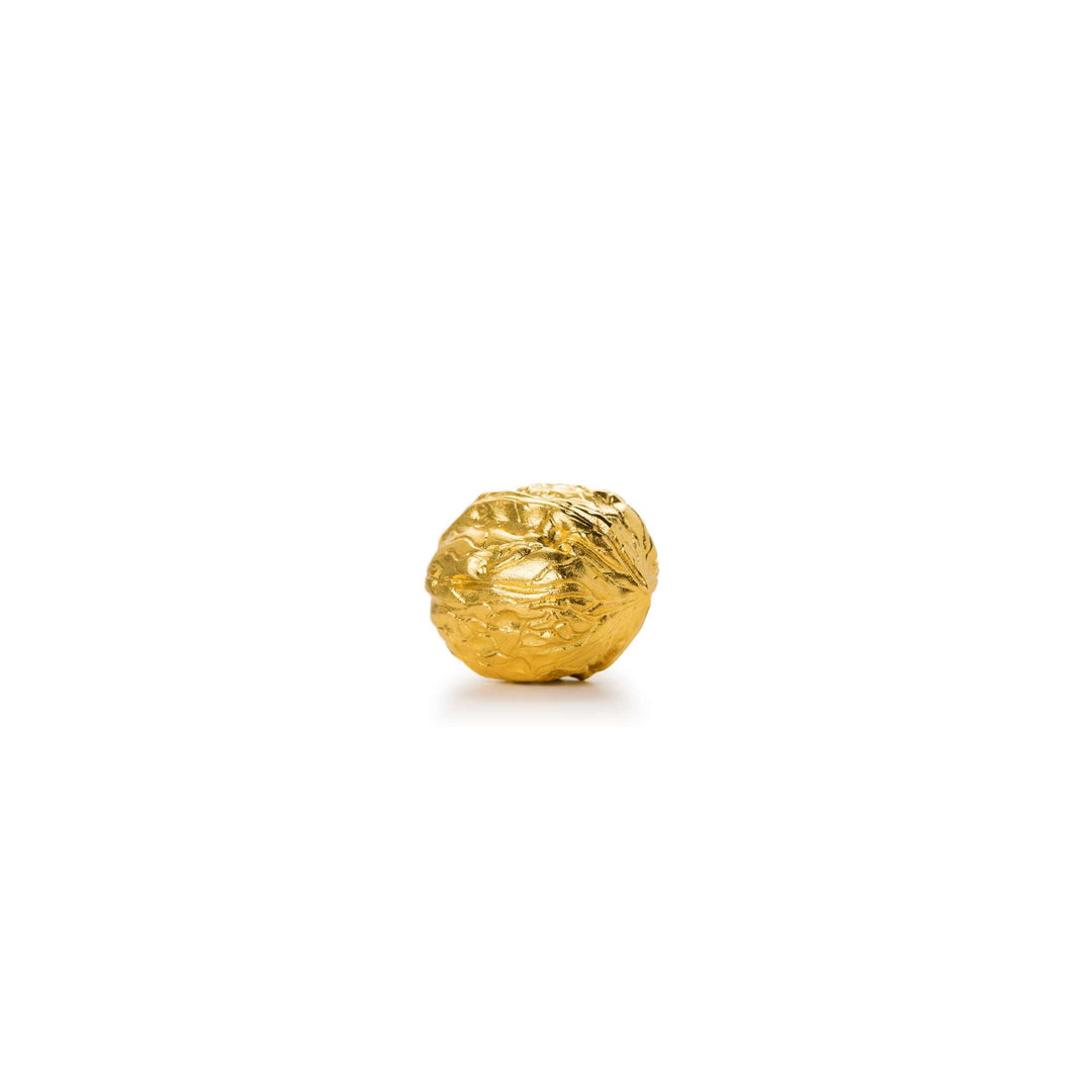 Risis Golden Harvest Walnut - A textured, golden sphere with intricate dimples and patterns rests against a plain, light background, its metallic surface reflecting light and creating shadows within the crevices.