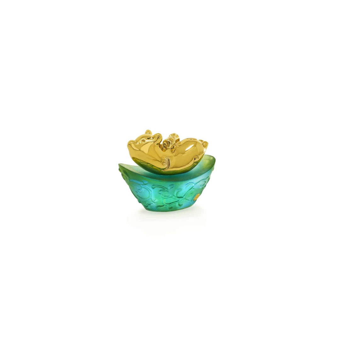 Risis Mini Celestial – Pig on Green Liu Li - An ornate golden flower rests inside a translucent teal bowl with intricately carved details, presenting a striking contrast of color and texture.