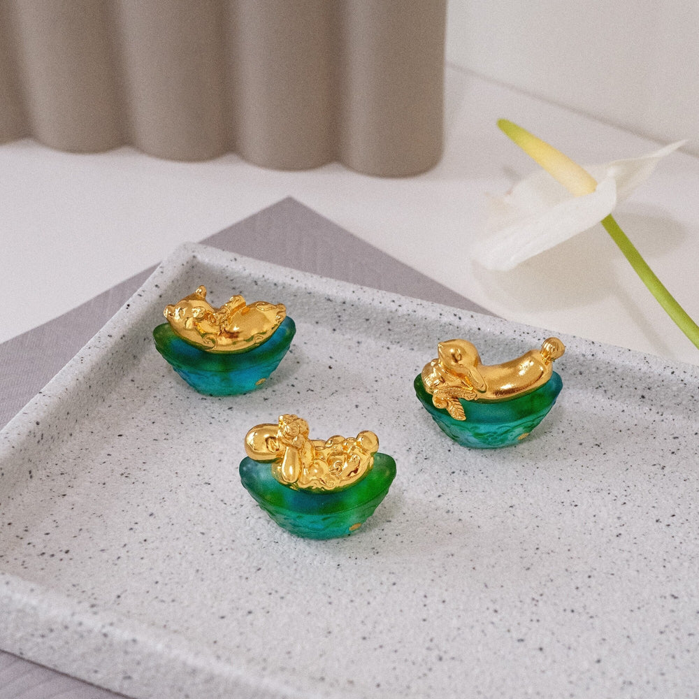 Risis Mini Celestial – Rabbit on Green Liu Li - Three small, green translucent bowls with gold-colored mermaid figures perched on the edges, displayed on a square surface.