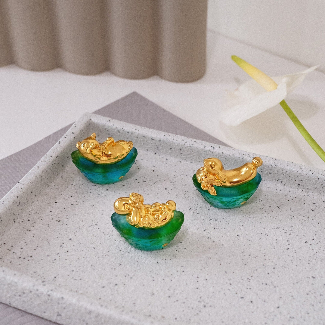 Risis Mini Celestial – Rabbit on Green Liu Li - Three small, green translucent bowls with gold-colored mermaid figures perched on the edges, displayed on a square surface.