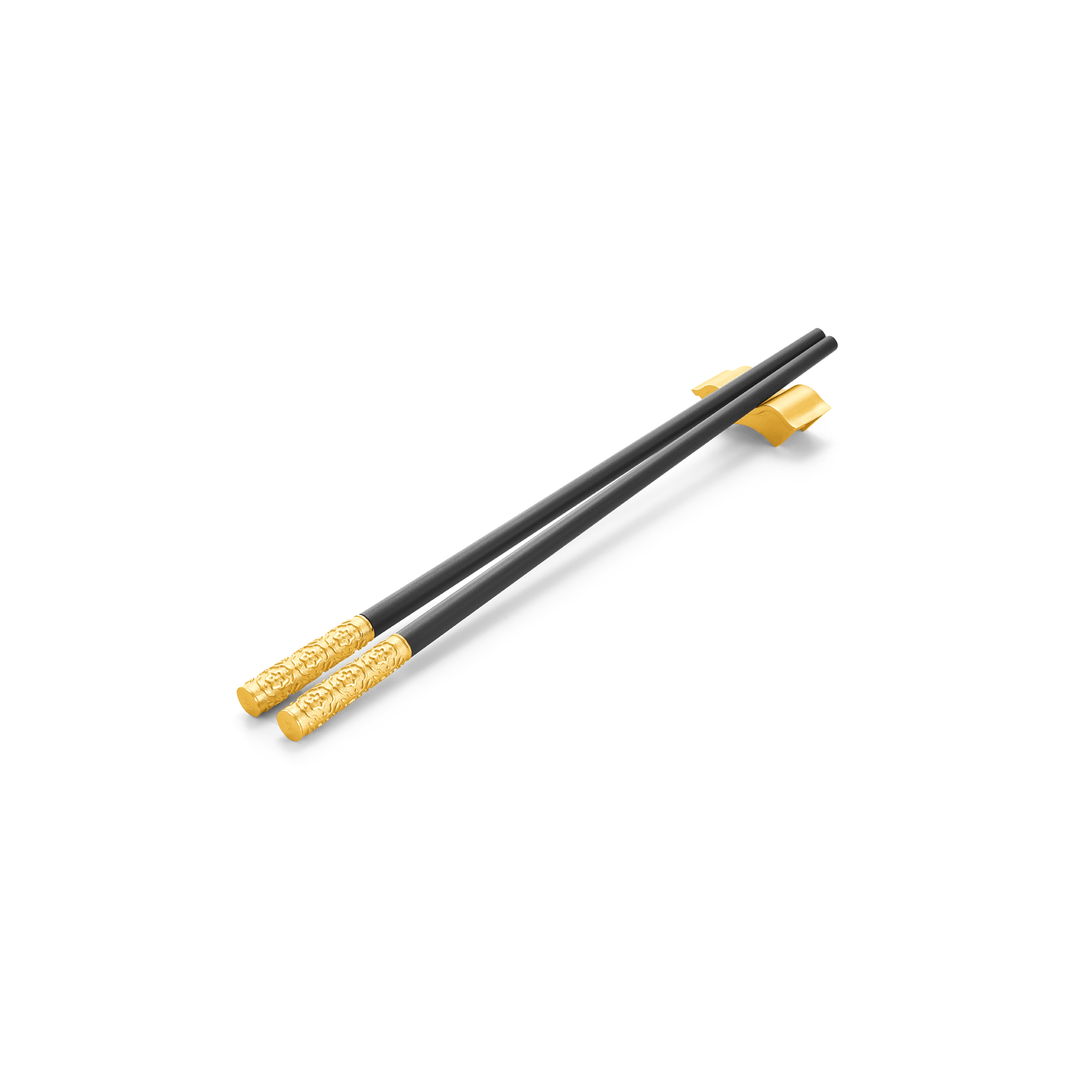 Risis Peranakan Chopsticks with Rest I - A pair of elegant black chopsticks with ornate golden detailing near the ends, resting on a stand against a light background.