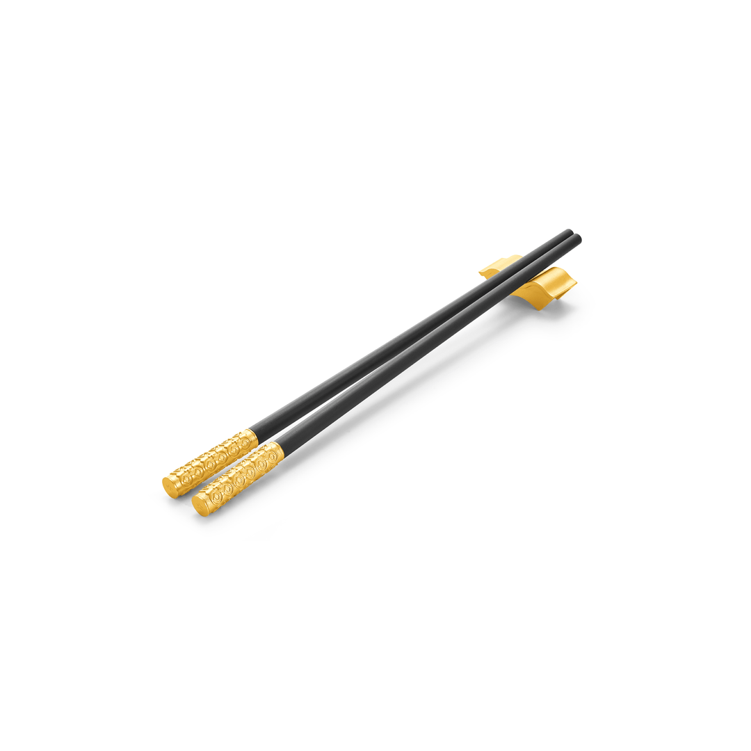 Risis Peranakan Chopsticks with Rest II - A pair of sleek black chopsticks with ornate golden ends rests on a simple chopstick holder with a golden hue.