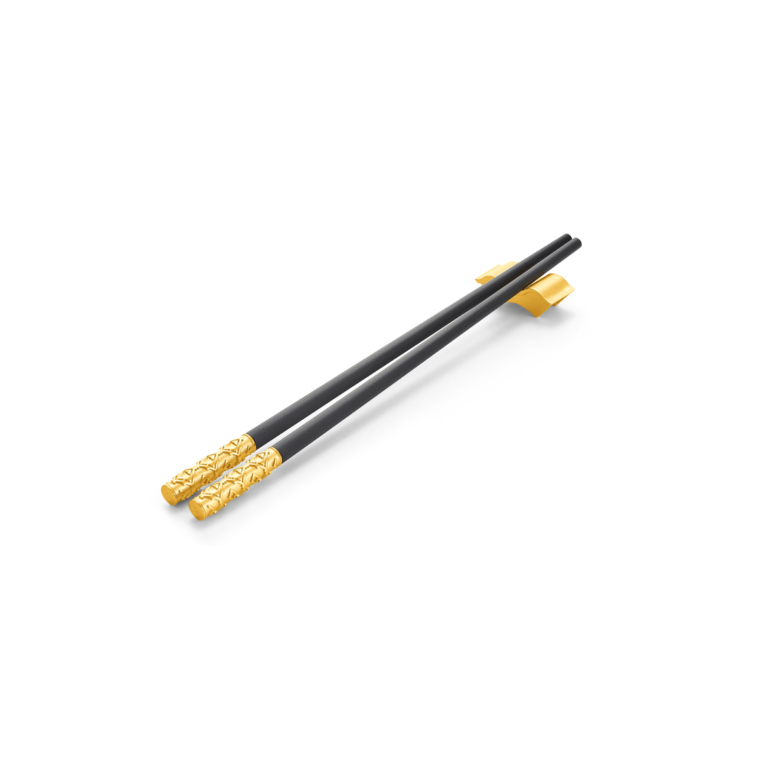 Risis Peranakan Chopsticks with Rest III - A pair of elegant black chopsticks with ornate golden details at the ends, resting on a yellow chopstick holder, conveying a sense of luxury and tradition.