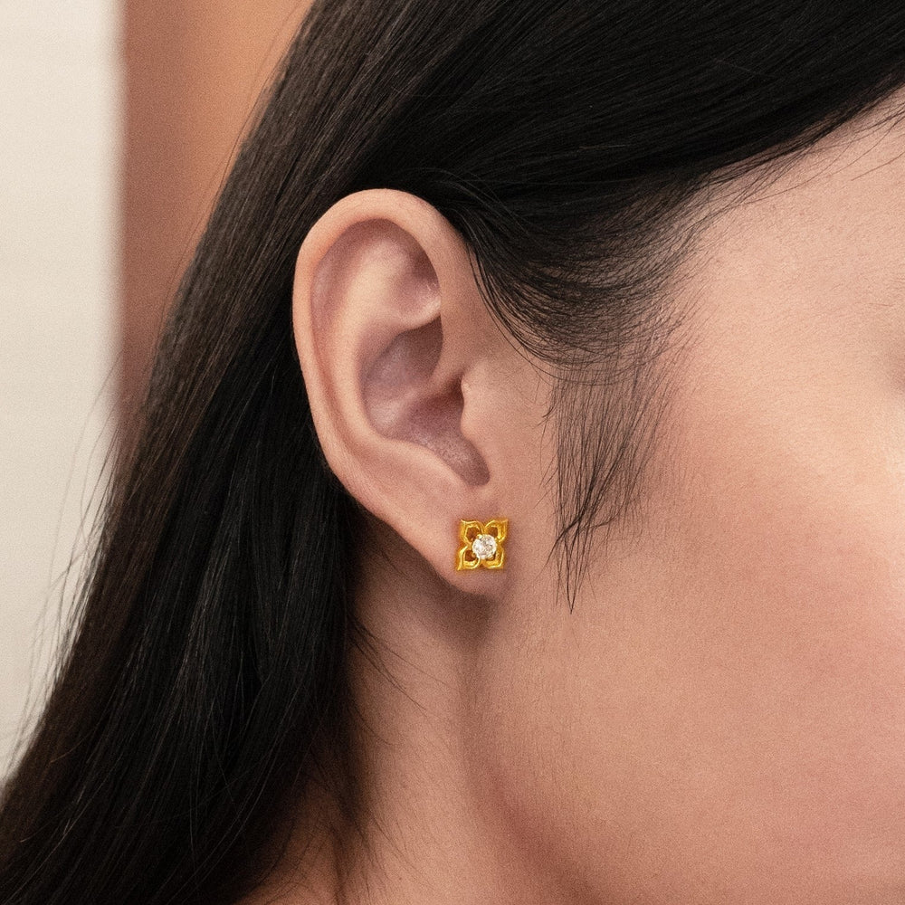 Risis Peranakan Earrings with White Topaz (G) - A golden square earring with a bear silhouette detailing is adorned on a person's earlobe, showcasing an elegant design.