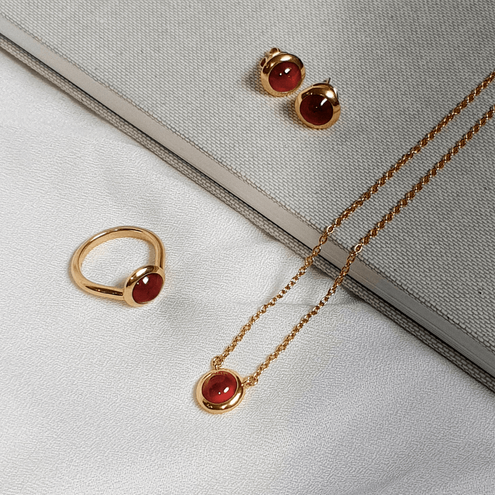 Risis Peranakan Jewel Ring with Red Garnet - A gold ring with a polished, central red gemstone set in a smooth rounded bezel, exuding elegance and simplicity.