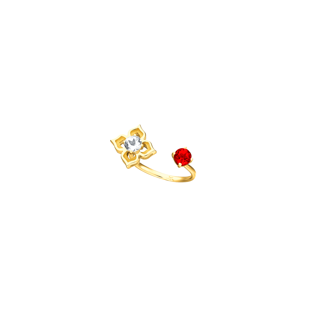 Risis Peranakan Moments Lace Ring with Red Garnet and White Topaz - A golden ring showcases a symmetrical floral design with a central clear gem, complemented by a solitary red gemstone set apart on the band.