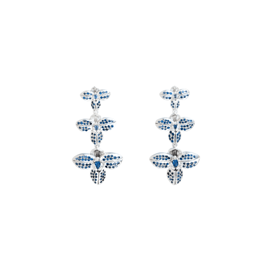 Risis Rare Orchid Earrings with Blue Sapphire - A pair of silver earrings with blue and white gemstones, designed in a repeating floral pattern with three flowers vertically aligned.