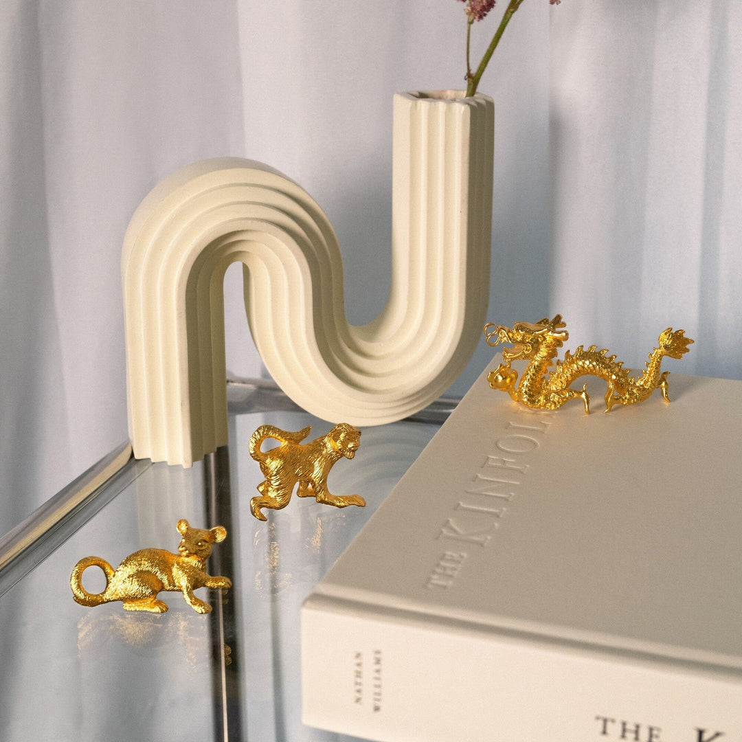 Risis Zodiac Rat Figurine - Golden figurines of a mouse, a monkey, and a dragon displayed intricately alongside an arched white vase on a reflective surface.